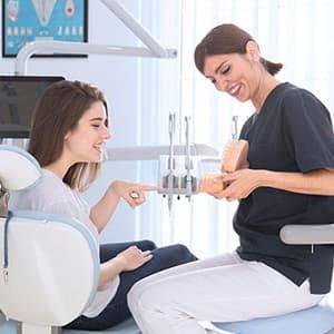 Female dentist and patient looking at prosthetics