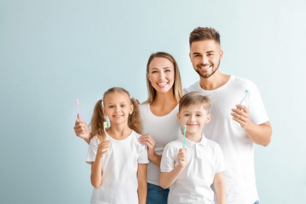 Young family of four all holding their toothbrushes